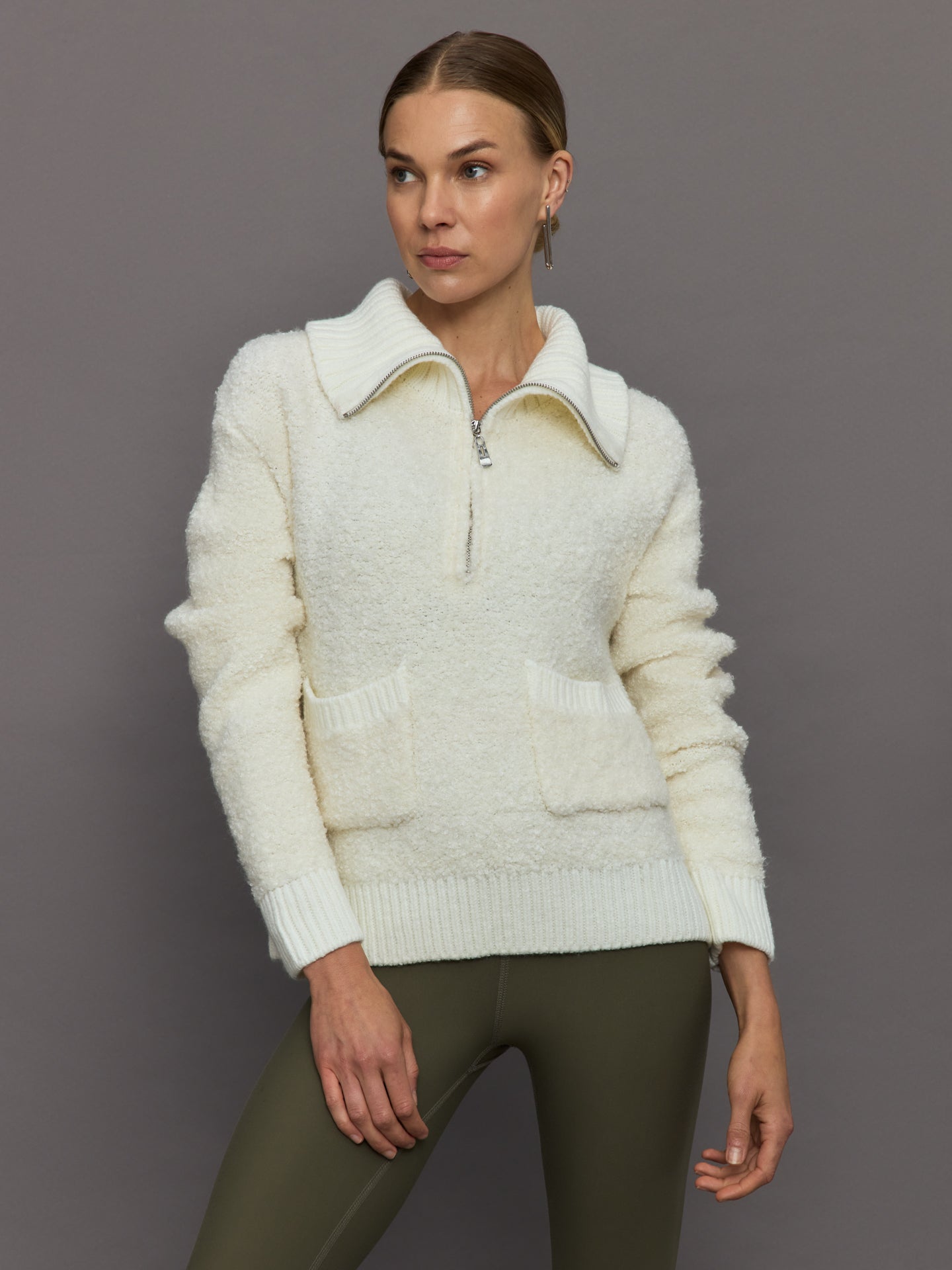 Model wears off white boucle pullover sweater with a half-zip front and high collar.
