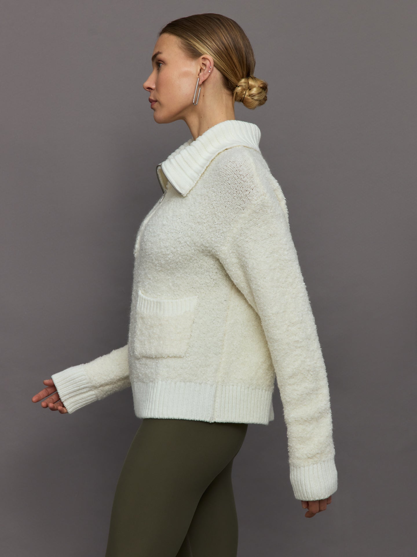 Model wears off white boucle pullover sweater with a half-zip front and high collar.