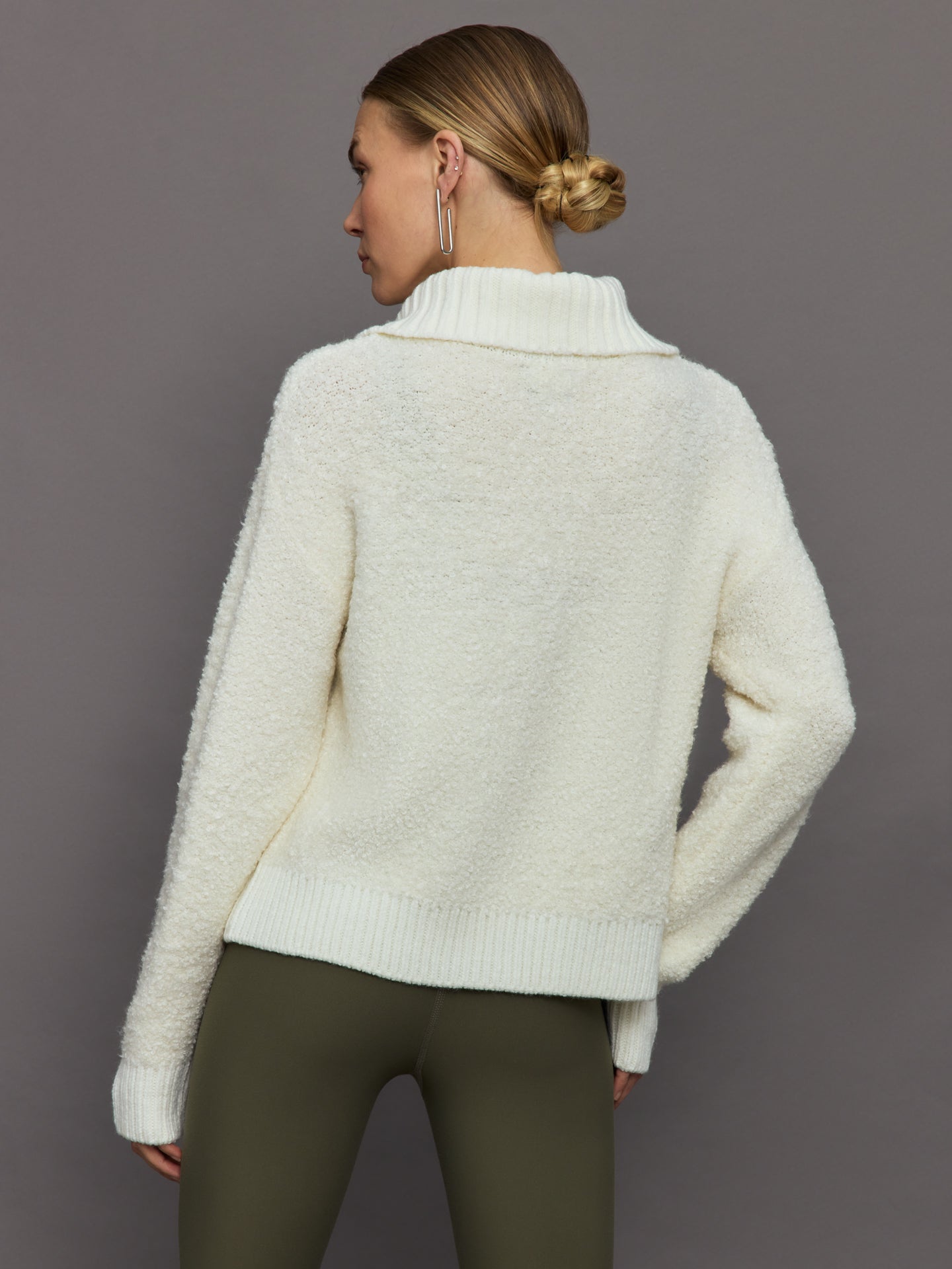 Model wears off white boucle pullover sweater with a half-zip front and high collar.