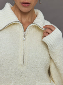 Model wears off white boucle pullover sweater with a half-zip front and high collar.