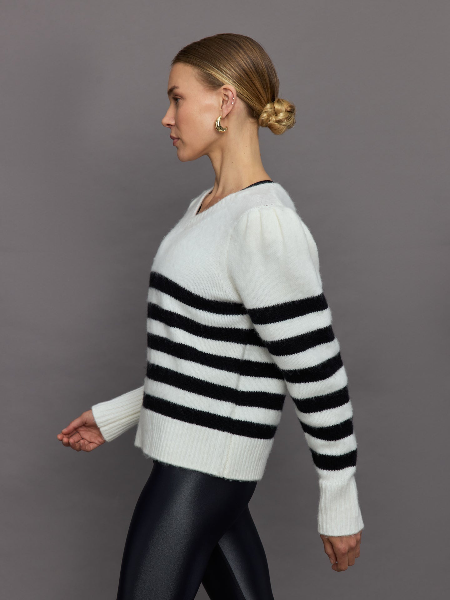 Model wears black and white striped sweater with v-neck.