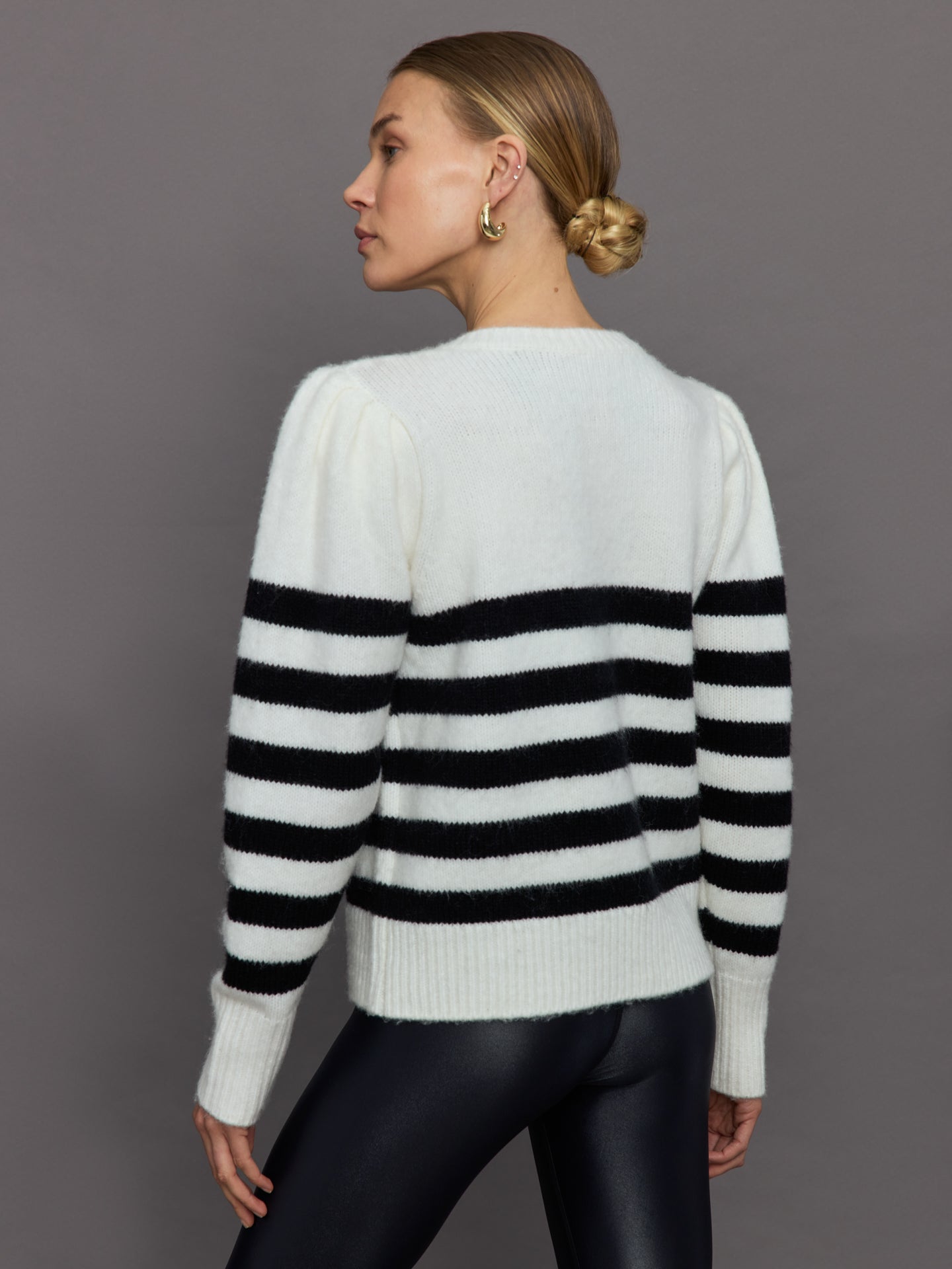 Model wears black and white striped sweater with v-neck.