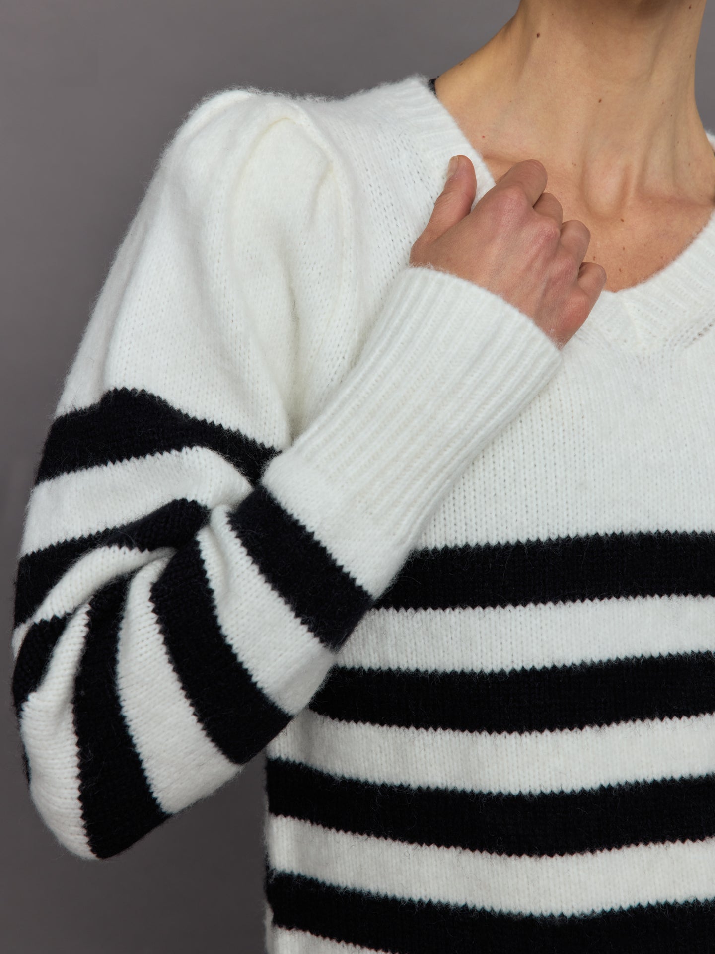 Model wears black and white striped sweater with v-neck.