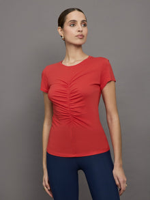 Model wears red short sleeve T-shirt with ruching down the center of the chest until the belly button. 