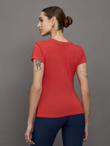 Model wears red short sleeve T-shirt with ruching down the center of the chest until the belly button. 