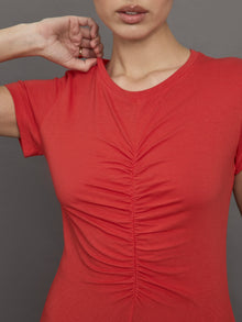 Model wears red short sleeve T-shirt with ruching down the center of the chest until the belly button. 