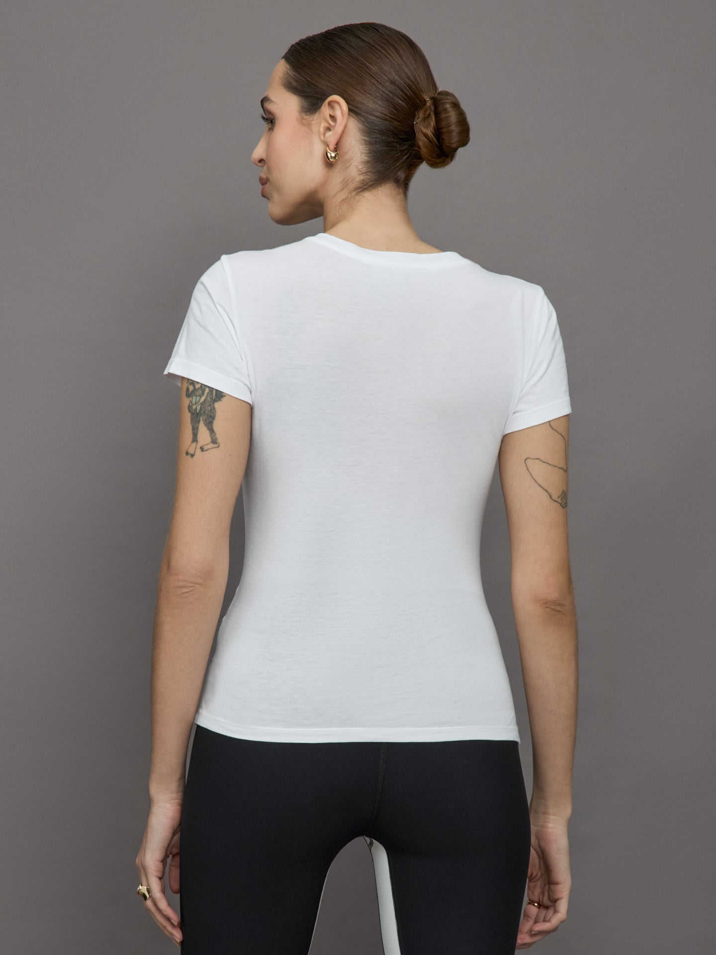 Model wears white short sleeve T-shirt with ruching down the center of the chest until the belly button. 
