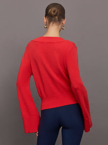 Model wears red off-shoulder sweater with bell sleeve.