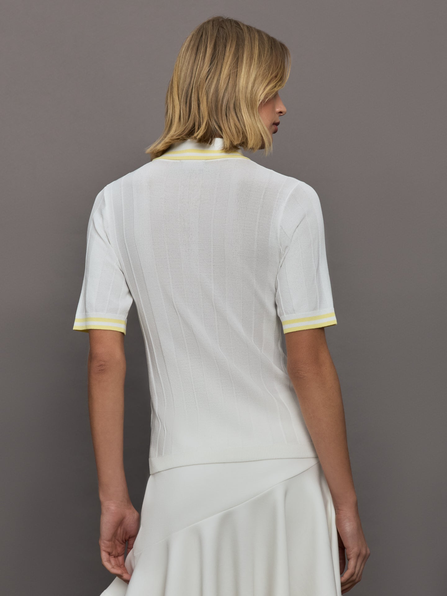 Model wears a lightweight and breathable polo tee shirt with yellow collar and sleeve details. 