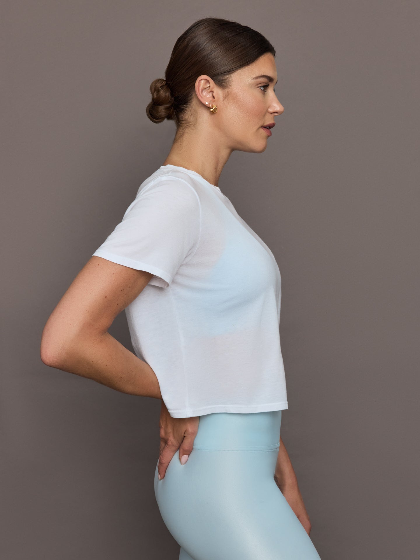 Model wears a cropped boxy white sheer tee shirt. 