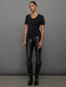 Model wears a black, short sleeve crewneck t-shirt with a front pocket and a relaxed, hip-length fit.
