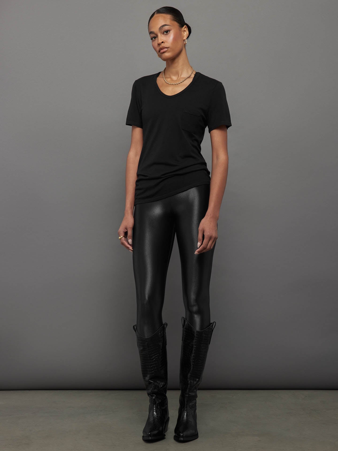 Model wears a black, short sleeve crewneck t-shirt with a front pocket and a relaxed, hip-length fit.
