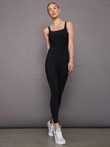 Model wears a black, fitted tank top with a wide scoop neckline and a smooth, soft-looking finish.
