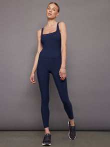 Model wears a navy blue fitted tank top with a wide scoop neckline and a smooth, streamlined look.
