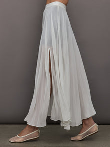 Side view of model wearing Mesh Pleated Skirt Ivory showing pleated drape and slit.