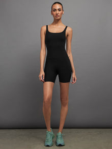 Model is wearing black Melt biker shorts styled with matching tank, full body view.