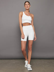 Model wearing Melt High-Rise Biker Shorts in White with one-shoulder sports bra, full body view.