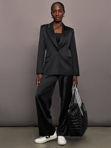 Model wears black satin pants with a relaxed fit.
