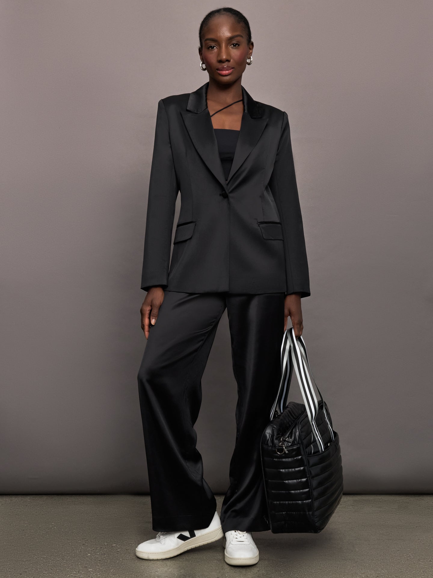 Model wears black satin pants with a relaxed fit.
