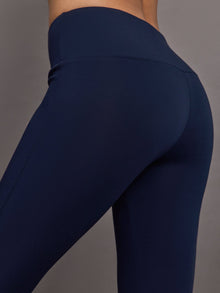 Navy high-rise pants with a fitted, sculpting silhouette through the hips and thighs, flaring out subtly at the hem.