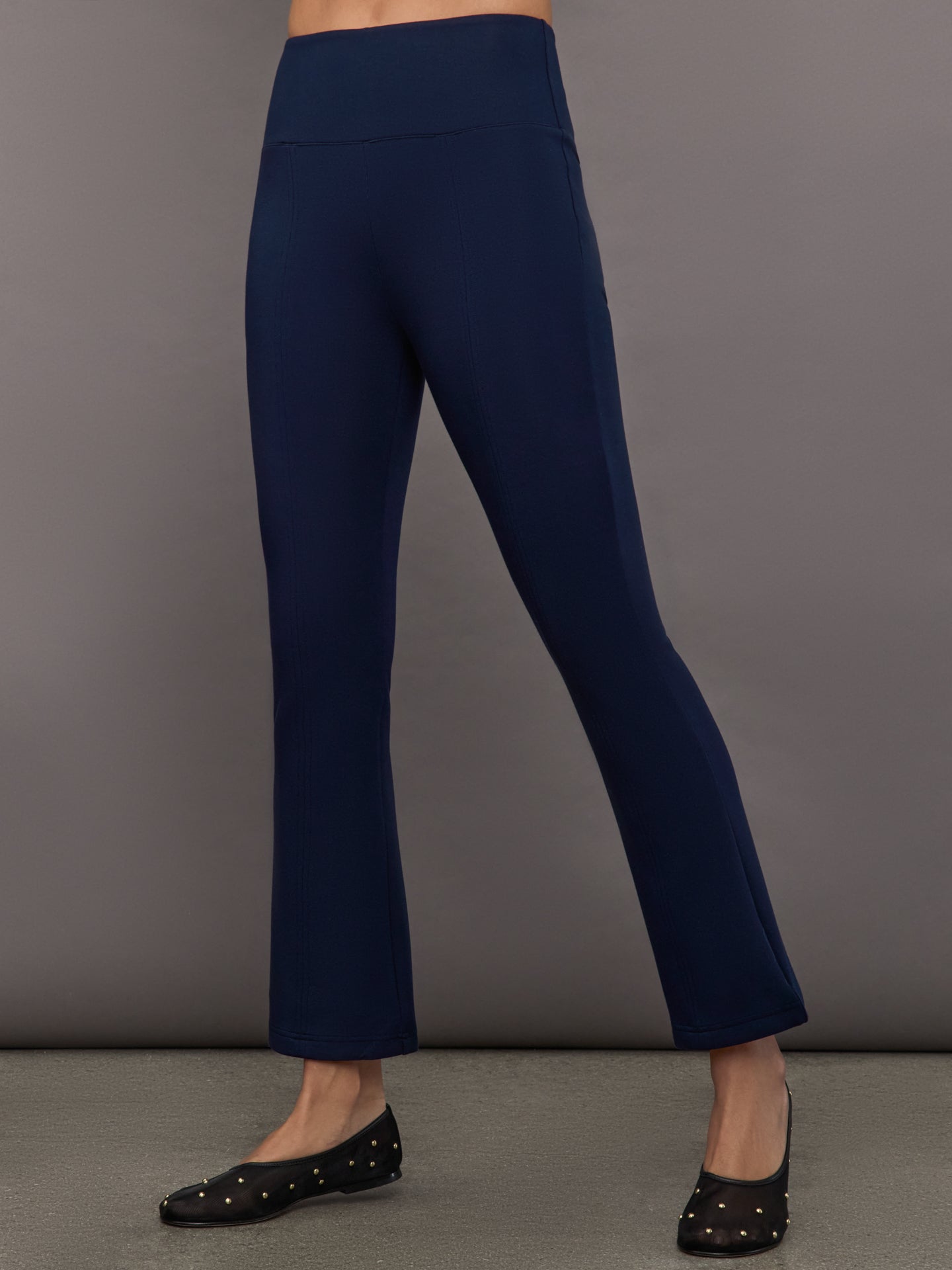 Navy high-rise pants with a fitted, sculpting silhouette through the hips and thighs, flaring out subtly at the hem.