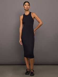 Woman wearing a black ribbed sleeveless dress against a gray background