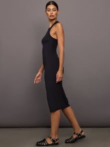 Woman wearing a black ribbed sleeveless dress against a gray background