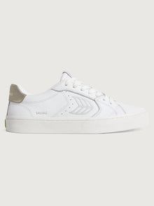 White sneaker with metallic gold heel and leaf logo on side. 