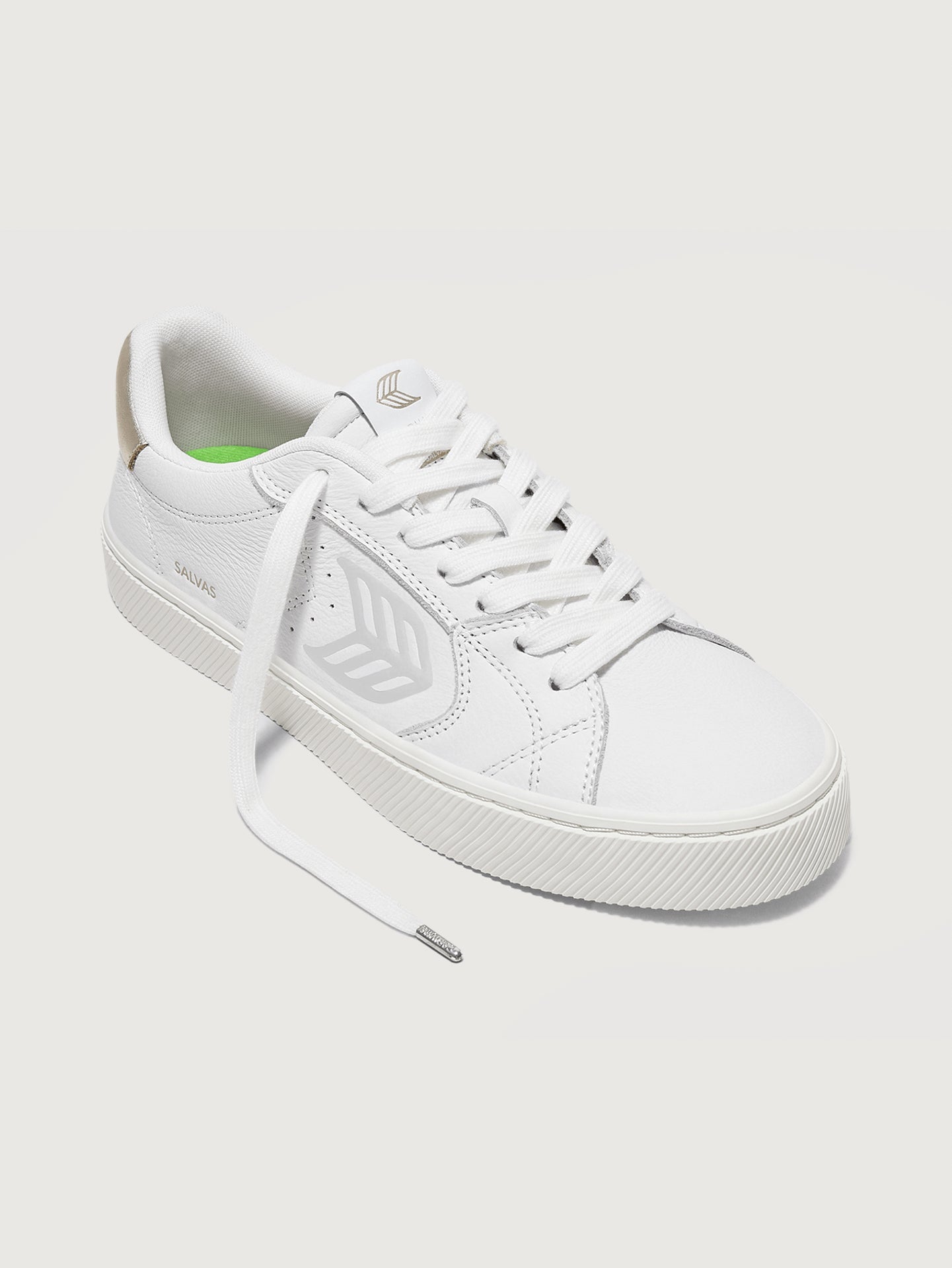 White sneaker with metallic gold heel and leaf logo on side. 