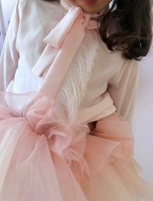 Close up of blush pink girls blouse featuring tie bow detail and soft tulle ruffle trim
