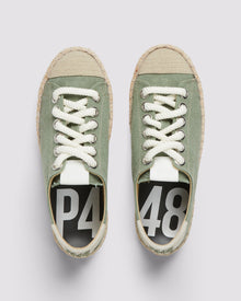 P448 green canvas sneaker with white rope laces and tan recycled suede heel tab, showcasing the organic jute sole and amber rubber tread from a front angle.