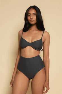 Charcoal bikini top with thin shoulder straps and underwire cups on a model with high-waisted black bikini bottoms.