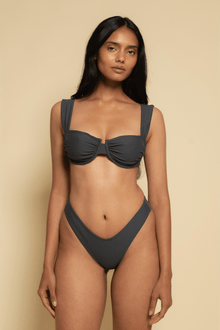 Charcoal bikini bottom with high-cut legs and zig-zag stitch detailing, shown on model.