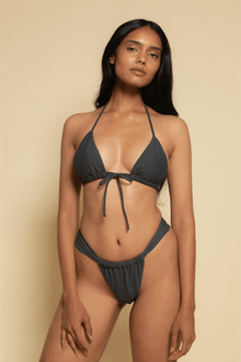 Charcoal bikini bottom with ruched sides and thin straps, shown on model against neutral background.