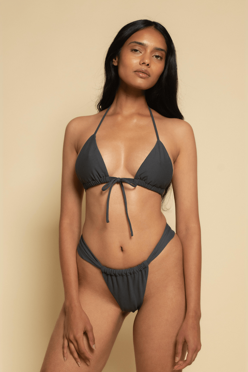 Charcoal bikini bottom with ruched sides and thin straps, shown on model against neutral background.