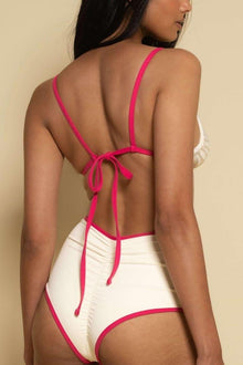 Cream bikini bottom with raspberry pink binding and tie straps at back.