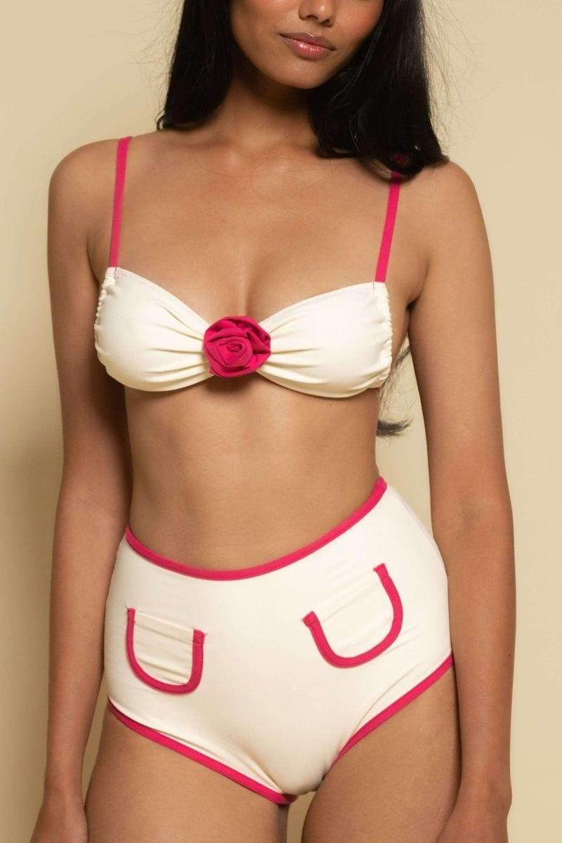 Cream bikini bottom with raspberry binding trim and decorative U-shaped pocket details.