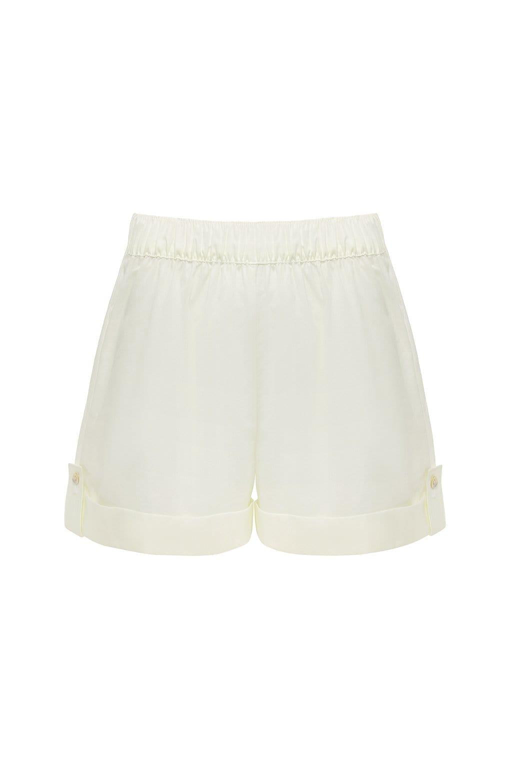 Cream-colored lounge short with elastic waistband and cuffed legs featuring side button details.
