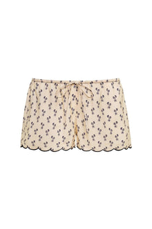 Cream shorts with small purple floral print and scalloped trim at legs, featuring drawstring waist.