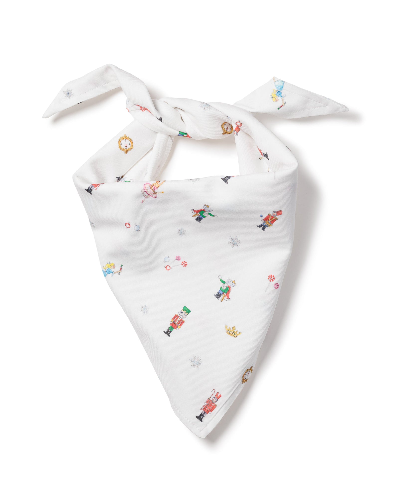 The Petite Plume Dog Twill Bandana in A Night at the Nutcracker features colorful holiday-themed illustrations like snowflakes, nutcrackers, a unicorn, a bird, and a crown. Its neatly folded into a triangle with tied ends.
