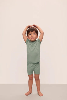 Model is wearing Kids TENCEL Modal Unisex Short PJ Set in Eucalyptus/Ivory