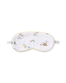 A young boy wears a Kid's Twill Sleep Mask in Easter Frolic, featuring colorful animal and nature prints, along with matching white pajamas. He smiles softly against a plain, light background.