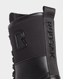 Close-up of the black Rudsak DAMIEN - M222500 men’s winter boot, showing the embossed logo on the pull tab and a raised R emblem. The insulated boot features matte, textured, weather-treated leather.