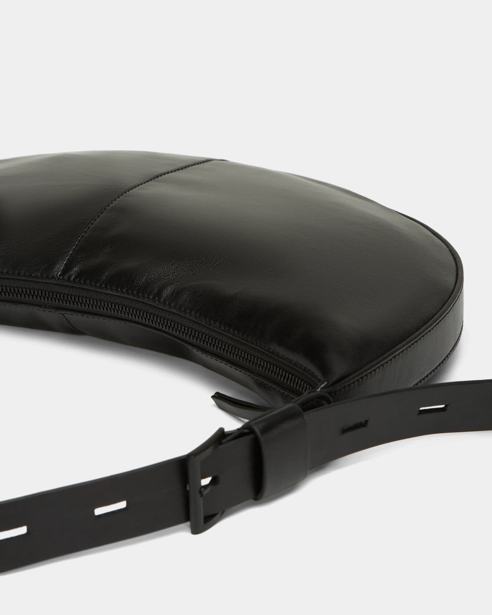 A close-up of the Rudsak LANISSA - 8324505 Black hobo bag, featuring a curved design, visible stitching, zipper closure, and an adjustable strap with rectangular holes—perfect as a chic womens crossbody accessory.