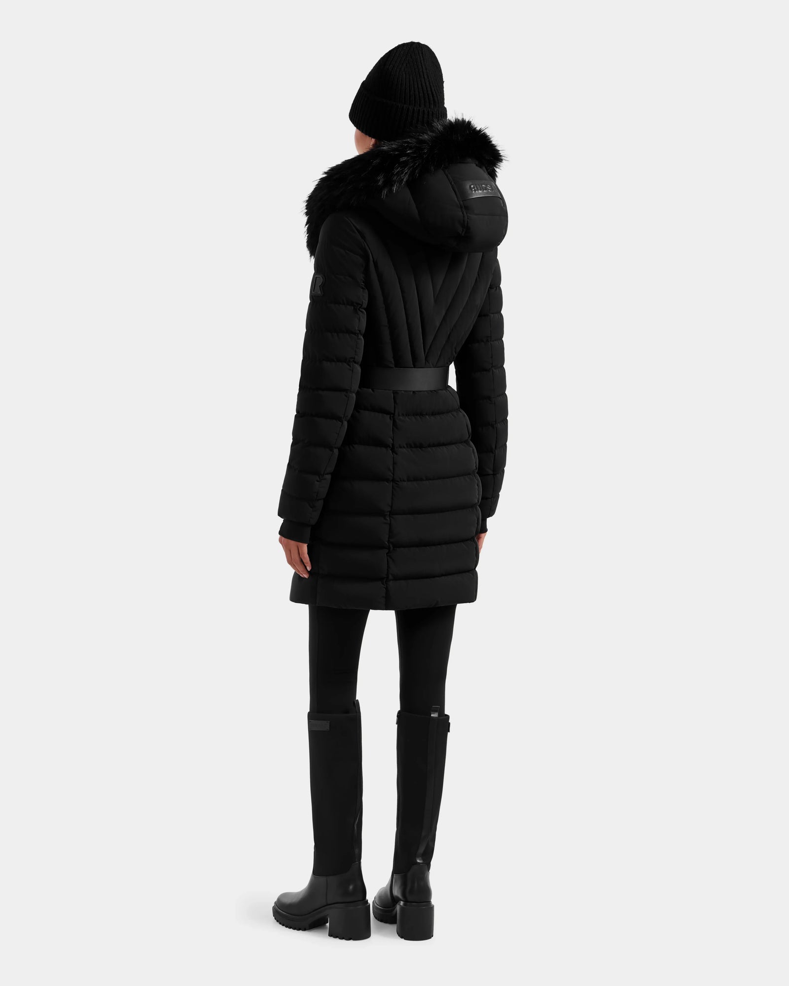 A person wearing the Rudsak ALISA M - L125586 Black quilted down parka stands with their back to the camera, set against a plain light background.