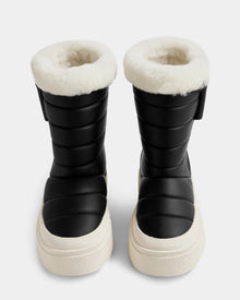 The Rudsak KATHIE - L225516 Black vegan leather winter boots feature thick white fur lining and chunky white soles, displayed front-facing on a plain light background.