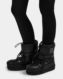 A person wears black leggings and Rudsak KIKA - L224506 Black women's winter boots, featuring chunky rubber soles, laces, an 