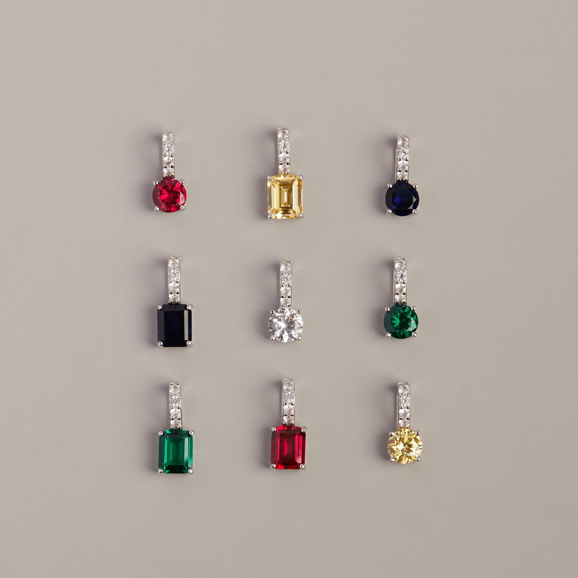 Model. Set of earrings with colored gemstones on a gray background