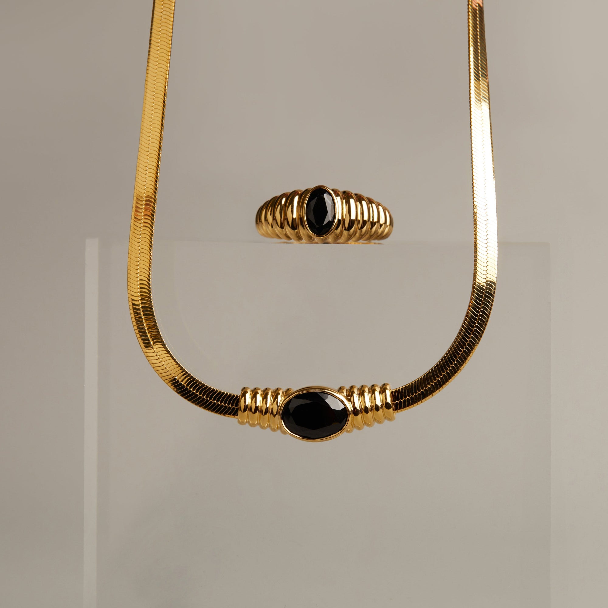 Model. Gold necklace with black beads on a gray background