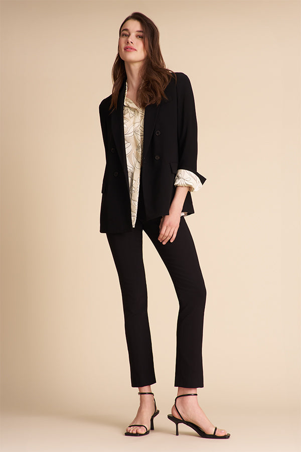 Person wearing black pants and a patterned top on a beige background | Exclude